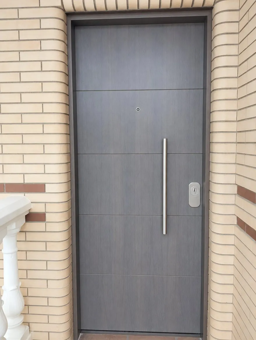 Blindada reforzada en gris con líneas horizontales y tirador de barra, en la entrada de una casa